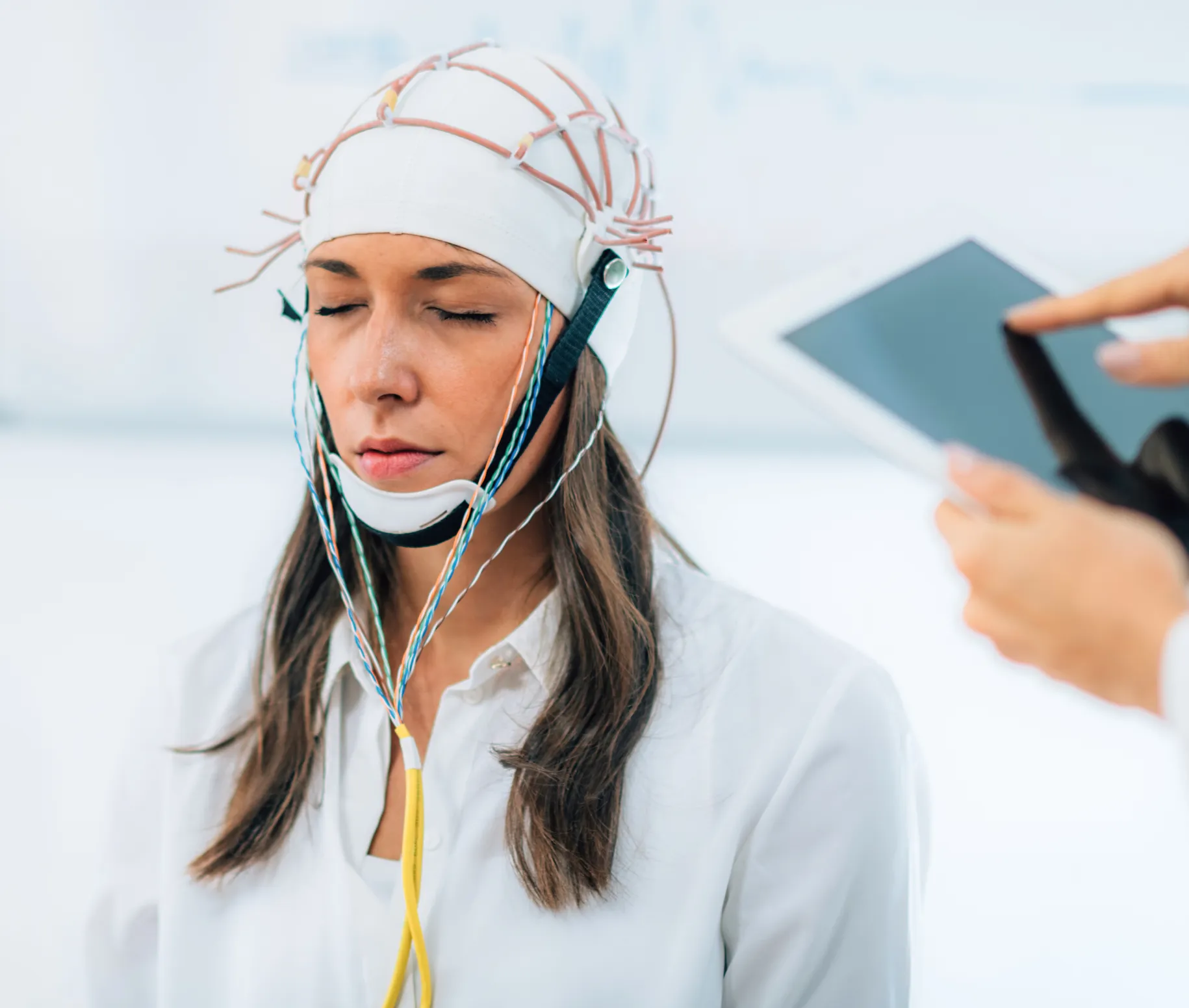 Woman in white shirt with a helmet on that has wires connected to a machine
