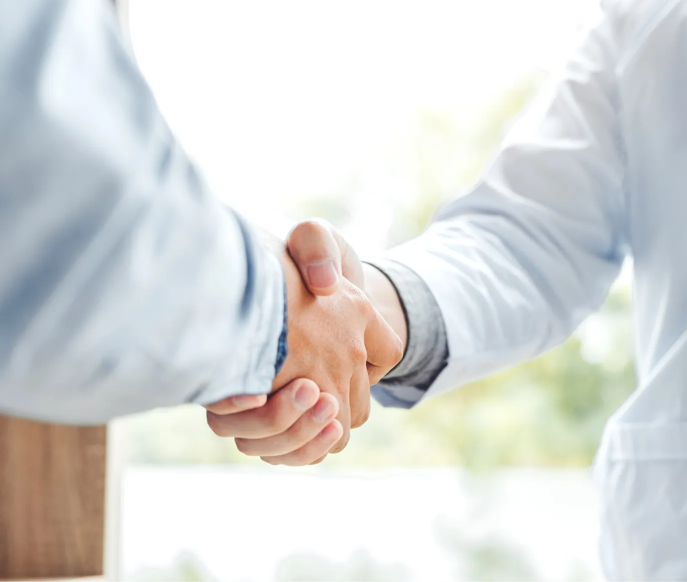 Two people in long white coats shaking hands