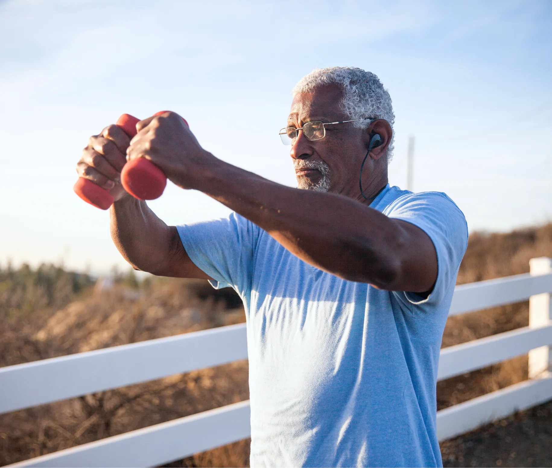 Man wearing headphones holding weights outdoors