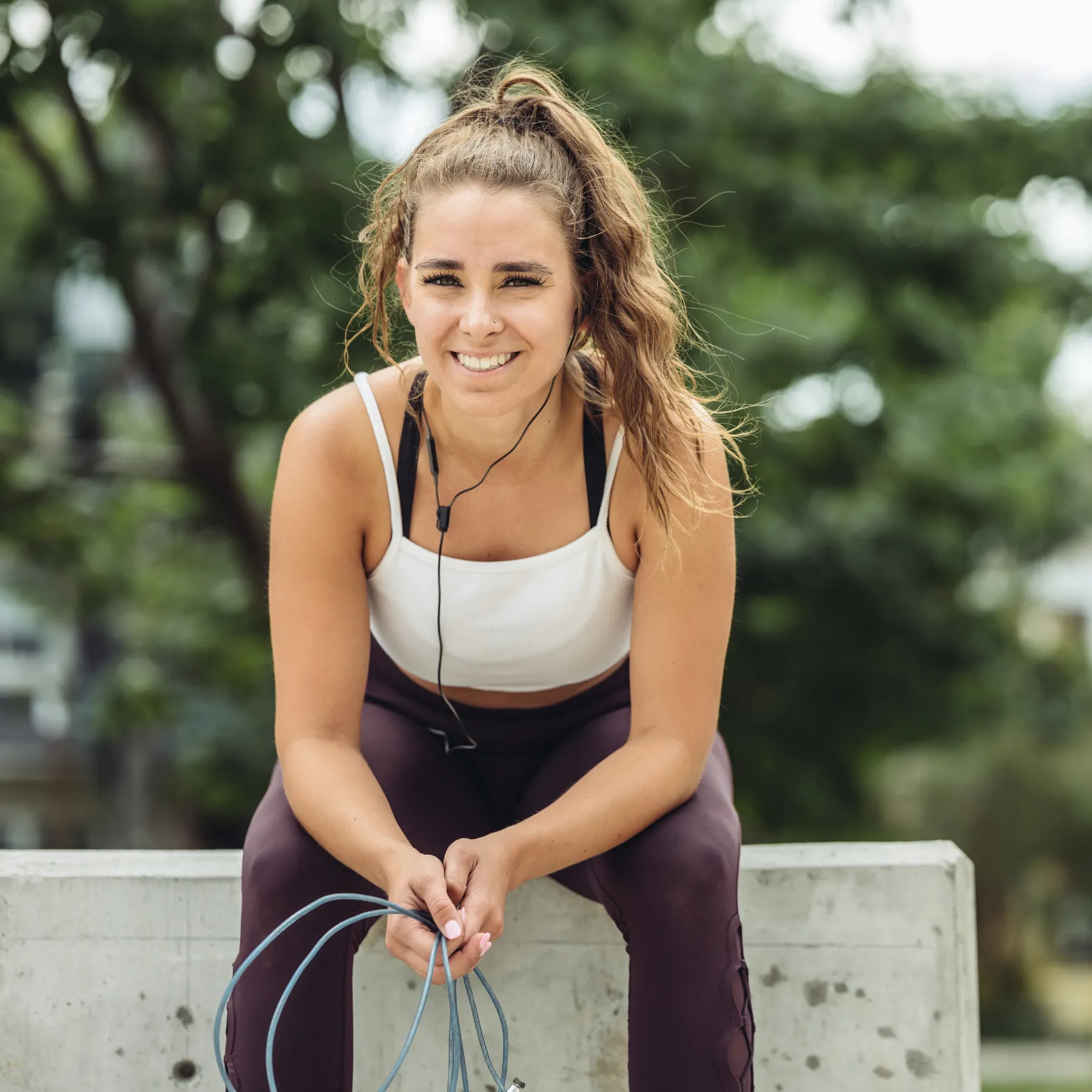 Woman sitting on curb smiling in workout clothes
