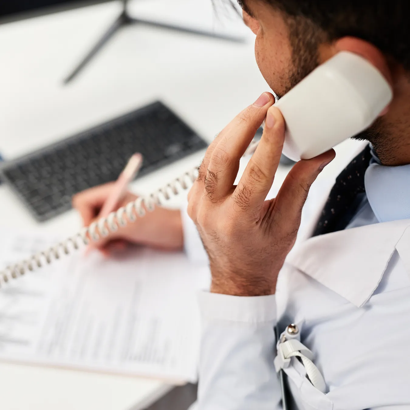 Woman answering the phone while writing on a desk