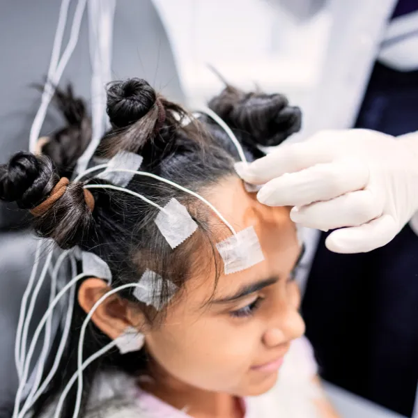 Child undergoing an EEG test with electrodes attached to the scalp, illustrating how Clinical Neurology Specialists diagnose and treat migraine conditions.